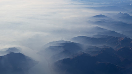 Obraz na płótnie Canvas Aerial view of the smog and fog that covers the Po Valley in Italy and the first mountains of the Alps. Landscape from airplane window. Pollution due to low rain and no wind