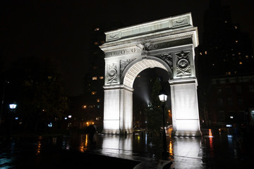 Fototapeta na wymiar Washington square park arch New York at night in the rain people silhouettes with umbrellas in the rain