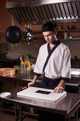 Portrait of a young Asian chef in a hotel restaurant. The process of making sushi maki rolls.