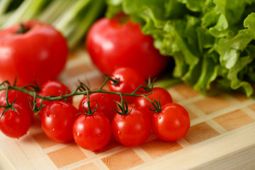 Cherry tomatoes lie on a cutting board in kitchen against backdrop of greenery healthy eating concept