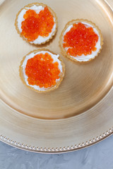 three tartlets with cream cheese and red caviar on a white background. the concept of a delicious Breakfast, buffet and snack. seafood dish. the view from the top. space for text.