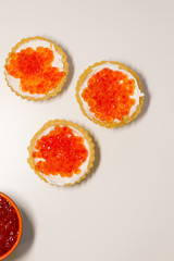 three tartlets with cream cheese and red caviar on a white background. the concept of a delicious Breakfast, buffet and snack. seafood dish. the view from the top. space for text.