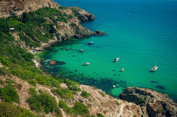 Obraz premium Stone Beach and Blue Lagoon with white yachts. Sea vacation. Summer season.