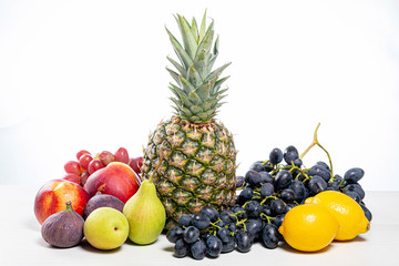 Obraz na płótnie Canvas Grapes, pineapple, pears, apples, nectarine, figs and lemons on white background