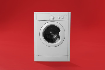 Modern washing machine on red background. Laundry day