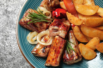 Delicious grilled ribs and garnish on grey table, closeup