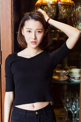 portrait of a young female wearing a black knitted sweater,standing by window.