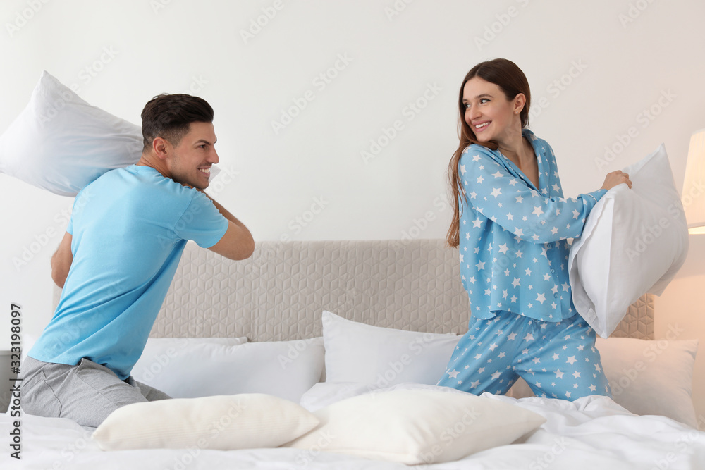 Poster Happy couple having pillow fight in bedroom