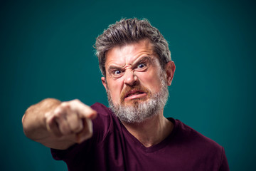 A portrait of angry bearded man pointing finger at camera. People and emotions concept