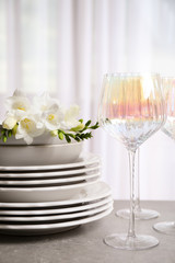 Set of glasses and dishes with flowers on light grey table