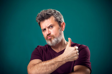 A portrait of bearded man showing thumb up gesture. People and emotions concept