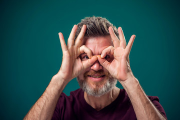 A portrait of bearded happy man showing owl gesture . People and emotions concept