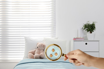 Woman with magnifying glass detecting bed bugs, closeup
