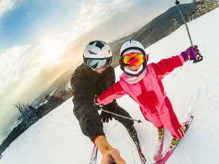 Portrait of cute girl wearing winter clothes while skiing with her father