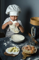 Boy with chef hat preparing dough - kneading and stretching