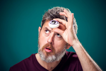 A portrait of bearded man holding egg with drawing eye behind forehad as third eye symbol.