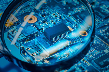 Chip on the computer's motherboard close-up through a magnifying glass. The concept of repair of...