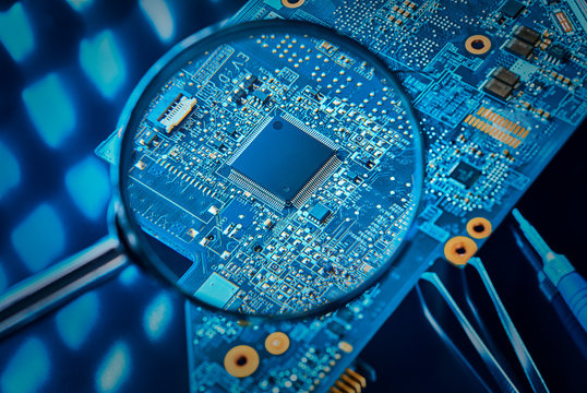 Chip on the computer's motherboard close-up through a magnifying glass. The concept of repair of the motherboard.