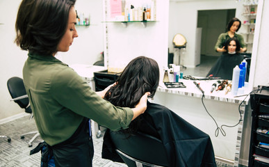 Beauty salon. Close up photo of a hairstylist touching hair of her beautiful female client.