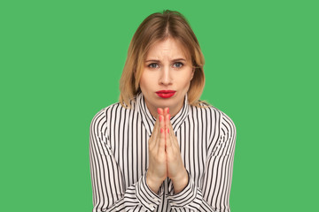 Attractive girl with beautiful red lips and in striped blouse holding hands together, praying to...