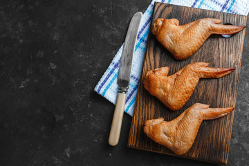 Smoked chicken wings on a wooden table with a towel and a dark background top view