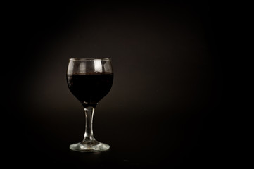 Glass with red wine shot on a dark background. Background for alcohol. Glassware for alcoholic beverages