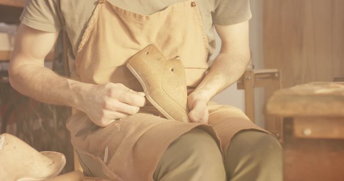 Traditional bespoke shoemaker cutting shaping marking leather insole on wooden shoe last with knife