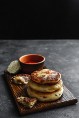 Potato pies with ketchup and garlic on a wooden Board. Dark concrete background, side view