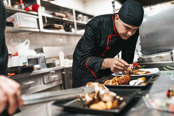 Professional chef arranging food plate with meat and vegetables.