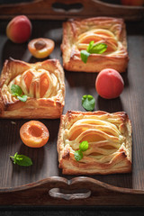Delicious puff pastry with powdered sugar and fresh peaches