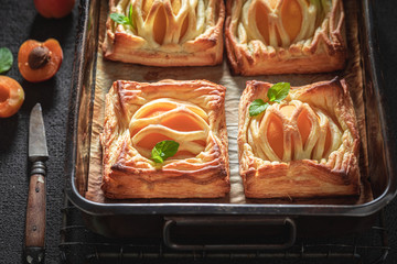 Yummy puff pastry with powdered sugar and fresh peaches