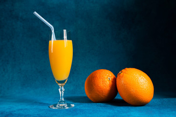 glass of orange juice and two oranges