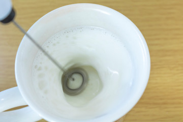 ミルク泡立て器と牛乳入りコップ