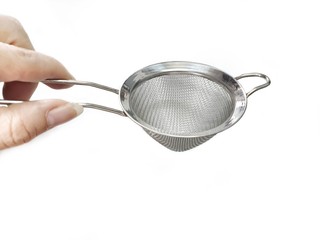 woman is holding stainless steel colander isolated on white background with copy space. kitchenware used for filtering raw materials