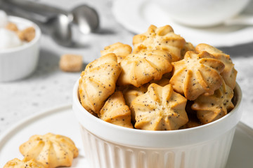Lemon cookies with poppy seeds in a white ceramic bowl on the gray kitchen table. Shortbread. Space for text
