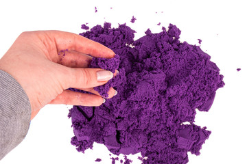 Purple  kinetic sand in hand isolated on a white background. Colored sand for modeling for children