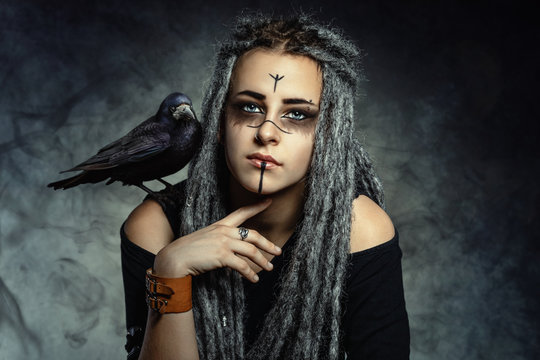 Portrait of a young woman with dreadlocks and with a raven on her shoulder