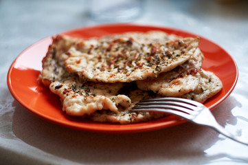 chicken fillet chop fried on a grill pan lying on a red plate