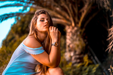 Lifestyle, a smiling young woman in a white dress on a palm tree in summer