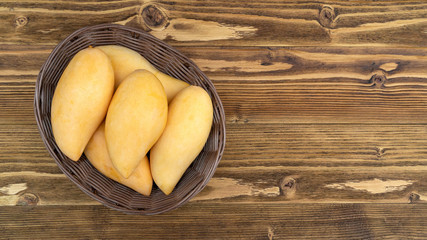Ripe Barracuda mango on a wooden table.