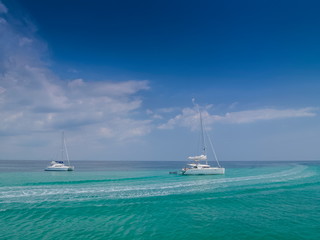 Sea view of two white yachts sailing in blue-green sea with cloudy and blue sky background, Phi Phi islands, Krabi, southern of Thailand.