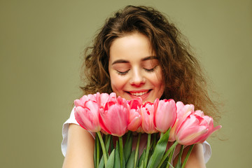 Young girl holding bouquet of pink tulips flower against green background