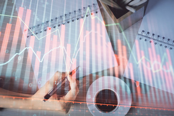 Multi exposure of woman's hands making notes with forex graph hologram. Concept of technical...