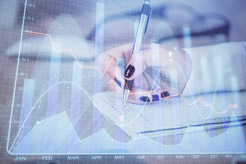 Multi exposure of hands making notes with forex chart huds. Stock market concept.