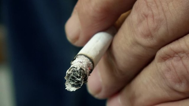 eine Zigarette in der Hand, die qualmt