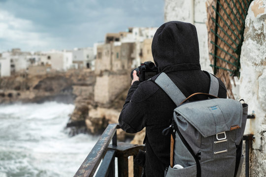 Photographer taking picture of a stormy sea in Polignano a Mare, Italy - Powered by Adobe