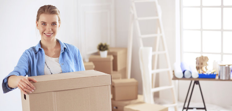 Young woman moving house to new home holding cardboard boxes