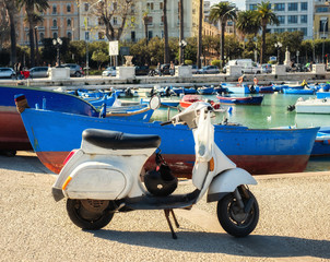 Old scooter near fishing boats in Bari, Italy