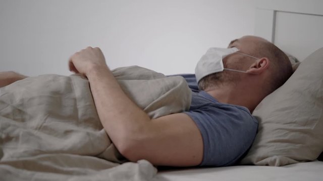 sick man is heated with fever lying in hospital room alone, hands and body are trembling by high temperature