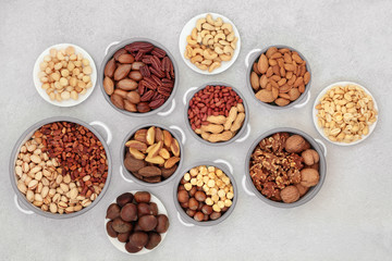 Dried nut health food collection suitable for a vegan  and vegetarian diet high in protein, omega 3, antioxidants, minerals and vitamins. Flat lay on mottled grey background.